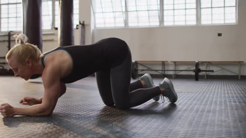 Side view of fit caucasian woman performing plank exercise at the gym