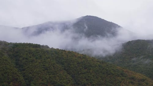 Wolken bedecken Berghügel im Herbst