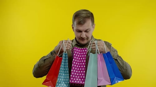 Man Holding Colorful Shopping Bags on Yellow Background