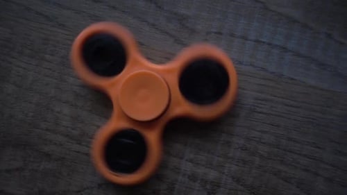 Orange Fidget Spinner Spinning on Wood Surface