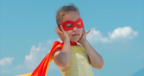Girl Dressed as Superhero Poses Against Blue Sky