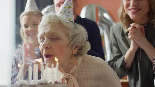 Family Celebrates Senior Woman Blowing Out Birthday Candles