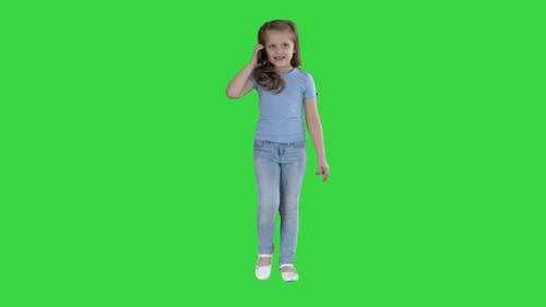 Little Cute Girl Making a Phone Call While Walking on a Green Screen, Chroma Key.