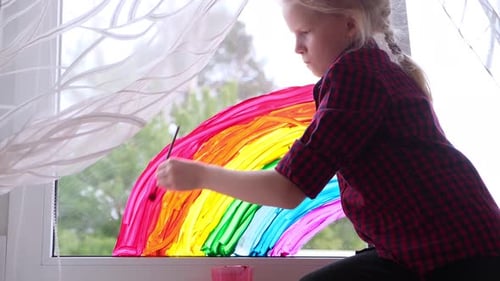 Girl Painting Rainbow on Window Brightly in Daytime