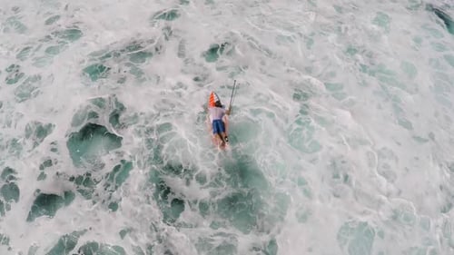 Aerial view of a man paddling while sup stand-up paddleboard surfing in Hawaii.