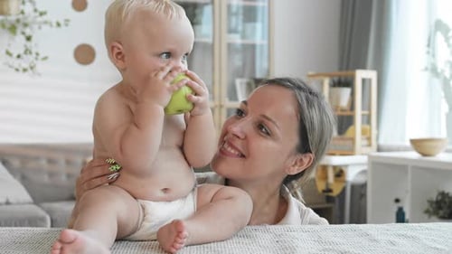 Baby Eating Apple with Smiling Adult Female
