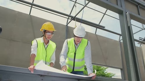 Asian colleague workers people wearing protective safety helmet and work at construction site.