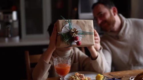 Child Plays With Gift at Dining Table With Adult