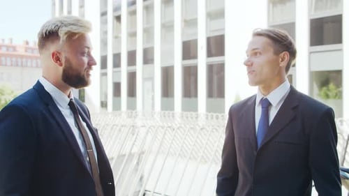 Confident businessman and his colleague in front of modern office building.