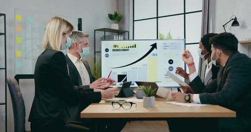 Business Team Reviews Financial Data Wearing Masks