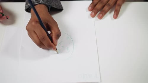 Hand Holding Blue Pencil Drawing on Paper