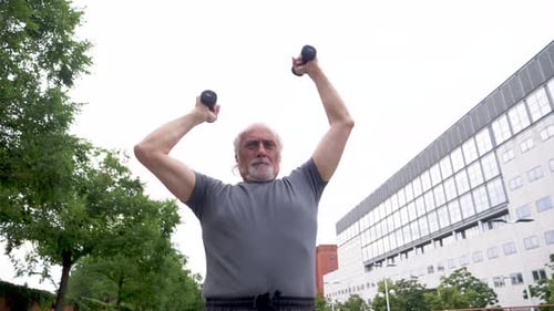 Slow motion shot of senior man with dumbbells during training in city