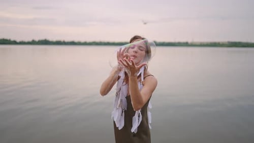 Woman Blowing Bubbles by a Rural Lake
