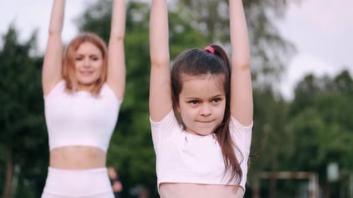 Woman and Child Exercising in Park Together