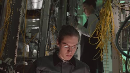 Young Adult Working on Laptop in Server Room