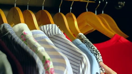 Hand Selecting Striped Shirt in Wardrobe
