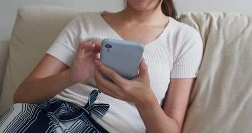 Woman Relaxing on Couch Using Smartphone