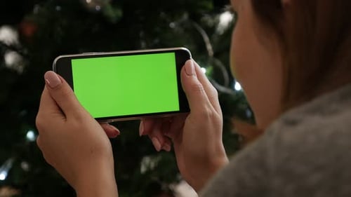Woman checks green screen smart phone on New Year night 4K 2160p 30fps UltraHD video - In front of