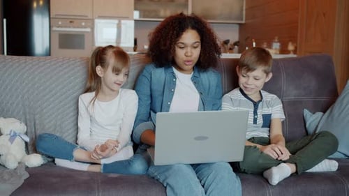 Happy Children Watch Laptop with Adult on Couch