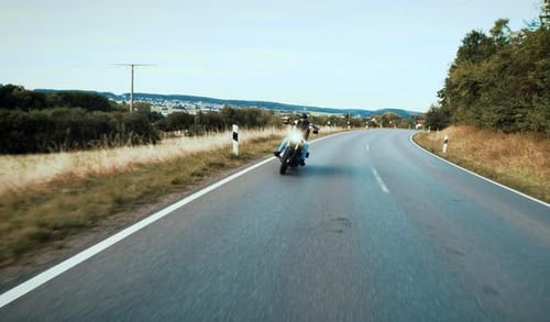 Motorcycle Driving Down a Country Road on Bright Day