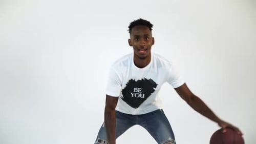 Tir au Ralenti d'un Afro-Américain dribblant un ballon de basket. Tourné en studio sur fond blanc