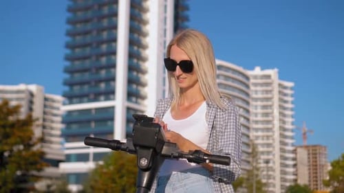Woman Using Phone With Electric Scooter in City
