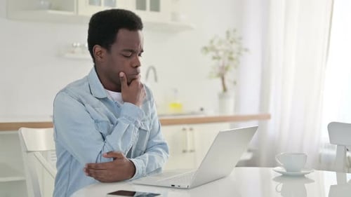 Young Adult Typing on Laptop in Kitchen