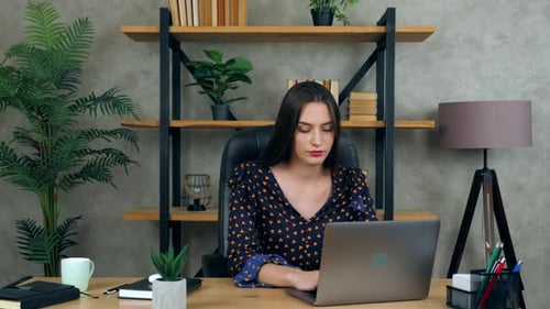 Beautiful brunette woman working at home office online uses laptop computer