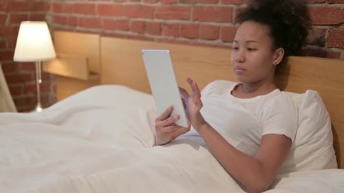 Woman Using Tablet While Relaxing in Bed