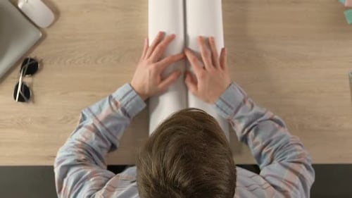 Traveler Unrolls World Map On Desk Top View