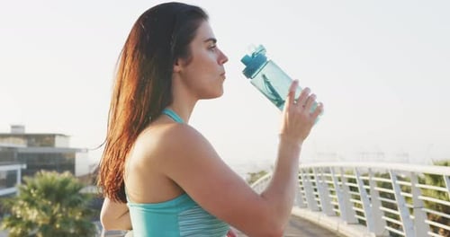 Athletic Woman Drinks Water in the Sunlight