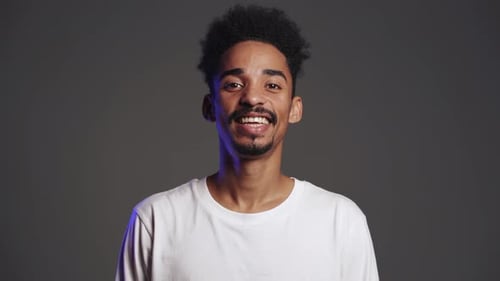 Handsome African American Man with Trendy Curly Hairdo on Grey Studio Background