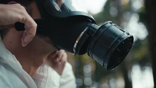 Man with White Suit in the Middle of the Woods Wears Black Gas Mask