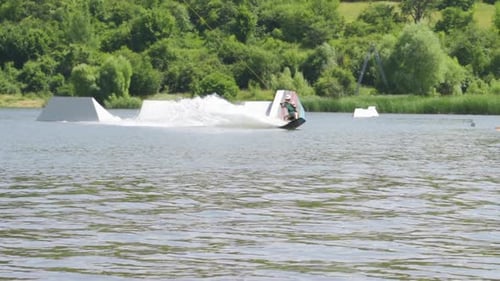 Athlethic Male Wakeboarder Doing Back Flip and Other Tricks Near Ramps