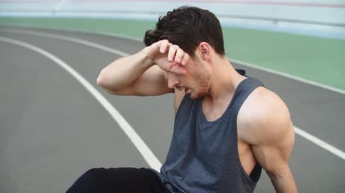 Portrait of Tired Man Resting After Running Workout on Track. Exhausted Runner