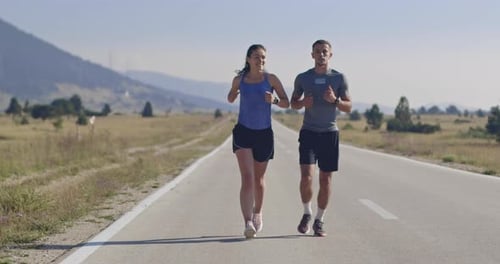 Tracking Slow Motion Shot of Sportive Couple Jogging Outdoors in the Morning Trail Running