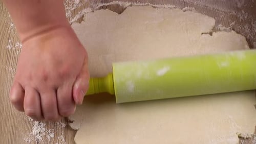 Hands Rolling Out Dough with Rolling Pin on Floury Surface