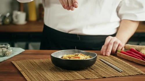 Chef Garnishing Noodles in Kitchen