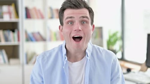 Surprised Man Celebrates Success in Home Office