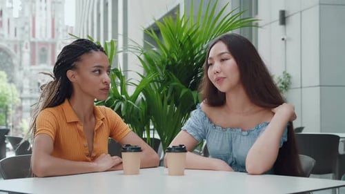 Two Women Chatting at Urban Cafe Table