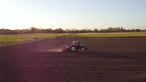 Tractor Working in Field at Sunset