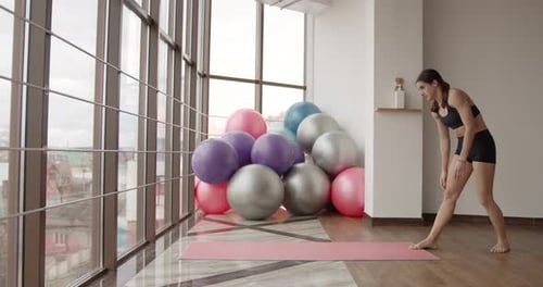 Athletic Woman Stretching on a Mat in a Fitness Studio