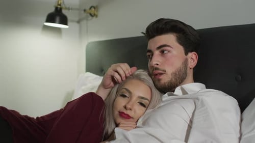 Mann streichelt den Kopf einer Frau, während sie zusammenliegen