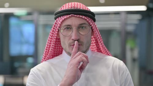 Hombre árabe de mediana edad poniendo el dedo en los labios