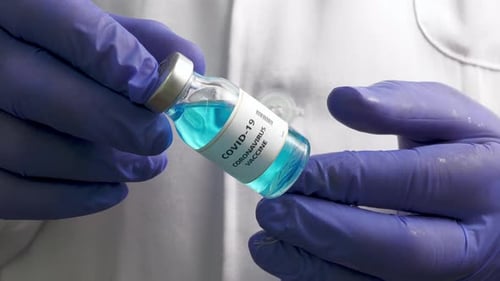 COVID-19 Vaccine Vial Held by Gloved Hands