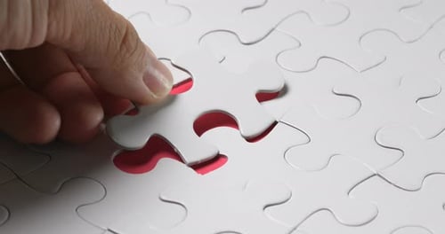 Hand put the last piece of jigsaw puzzle to complete the mission