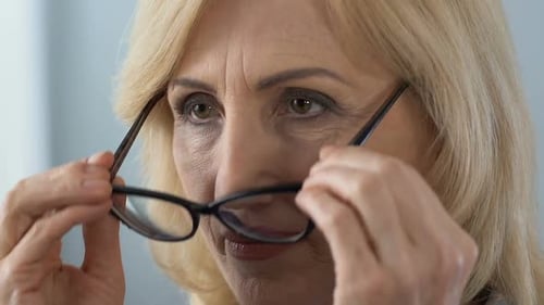 Mature Woman Puts on Glasses Close Up