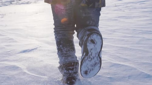 The Child's Feet Run on the Shiny White Snow That Glistens in the Bright Frosty Sun