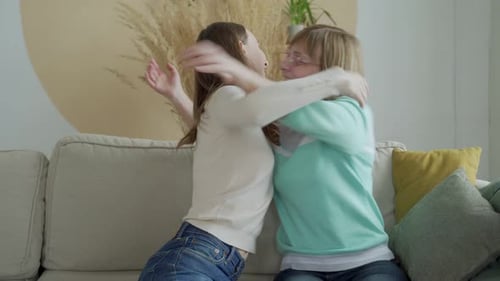Two Women Hugging on Couch at Home