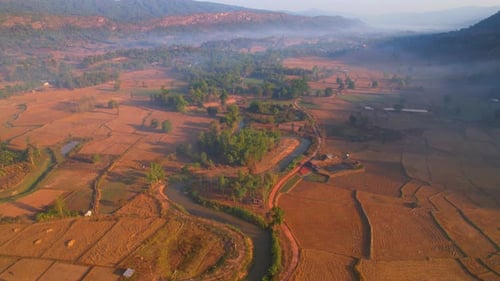Aerial view over villages and barren fields in countryside during sunrise